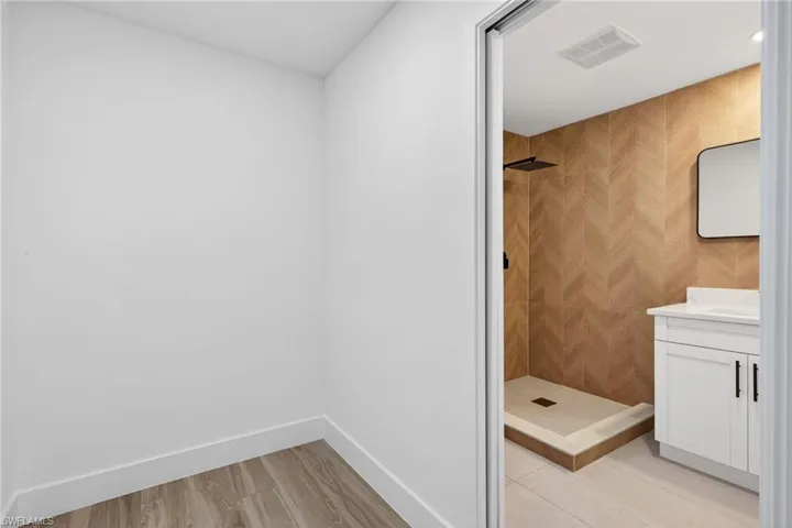 Bathroom with vanity, a shower stall, and light wood-type flooring