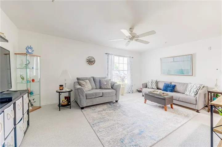 Living area featuring light carpet and ceiling fan