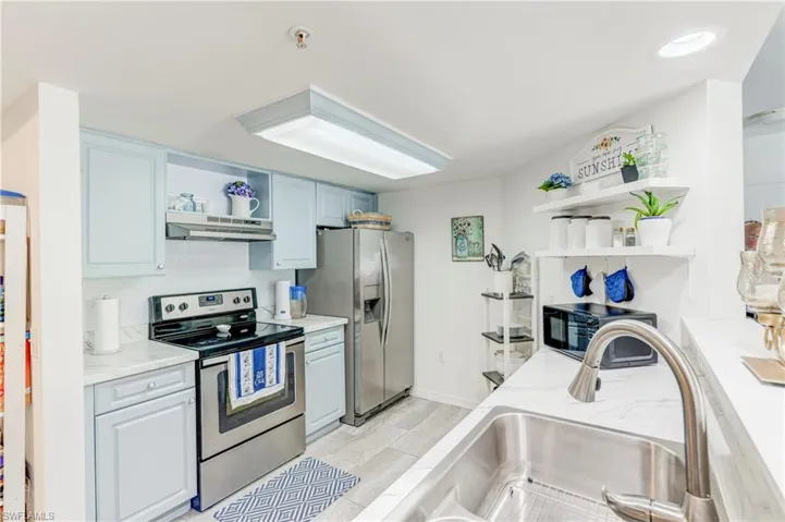 Kitchen with open shelves, stainless steel appliances, under cabinet range hood, a sink