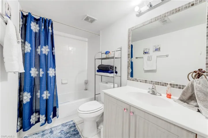 Bathroom with toilet, shower / tub combo with curtain, vanity, decorative backsplash, and tile patterned floors
