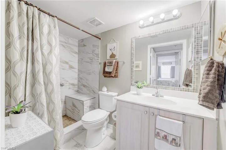 Bathroom featuring vanity, toilet, and curtained shower