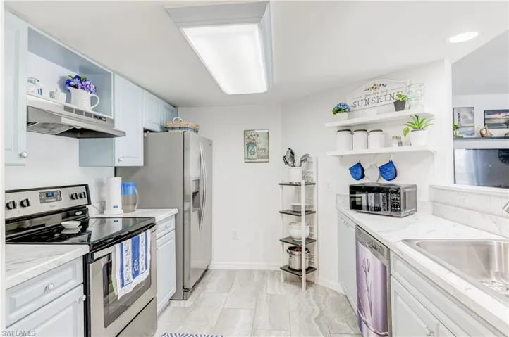 Kitchen with appliances with stainless steel finishes, open shelves, under cabinet range hood, light stone counters, and baseboards