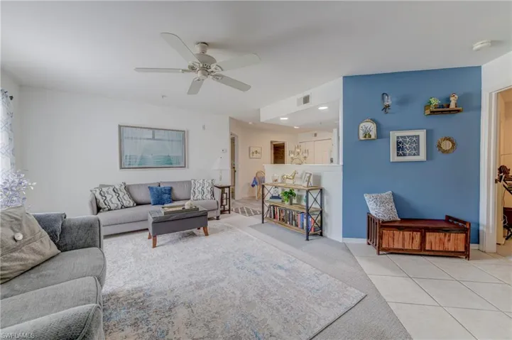 Living area featuring ceiling fan, light colored carpet, and light tile patterned floors