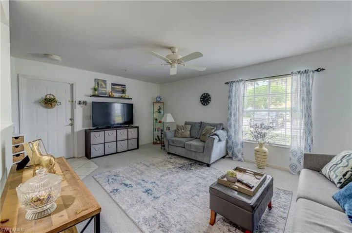 Carpeted living area with ceiling fan