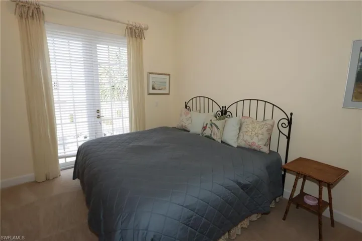 Carpeted bedroom with baseboards and access to exterior