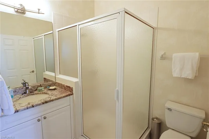 Bathroom with vanity, toilet, and a stall shower