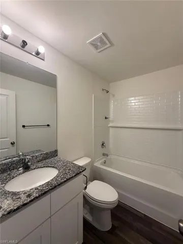 Bathroom featuring a white vanity with a granite countertop, undermount sink, and chrome faucet