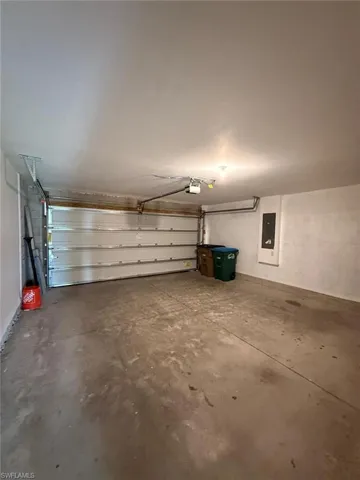 Spacious garage featuring a concrete floor, overhead lighting, and an automatic garage door opener