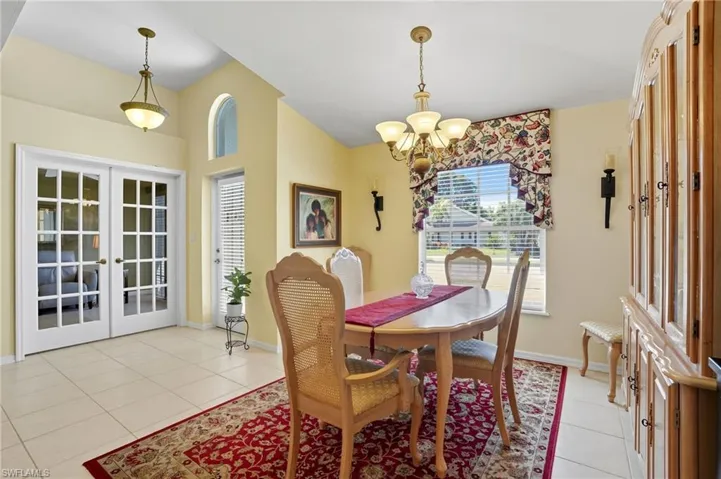 Dining room with french doors, light tile patterned flooring, plenty of natural light, and a chandelier