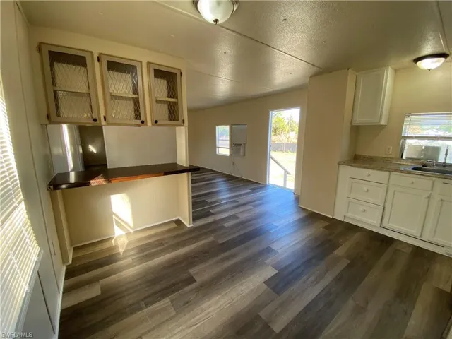 Unfurnished dining area with a textured ceiling and dark wood-style flooring