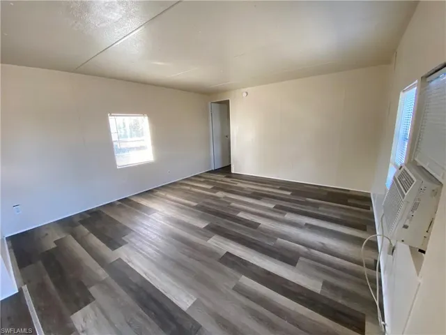 Spare room with dark wood-style flooring and cooling unit