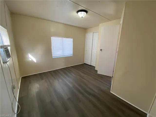Empty room featuring dark wood-style flooring and cooling unit
