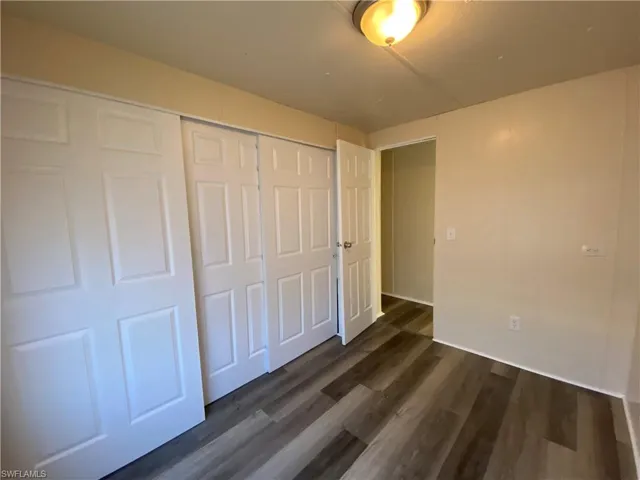 Unfurnished bedroom featuring a closet and dark wood-type flooring