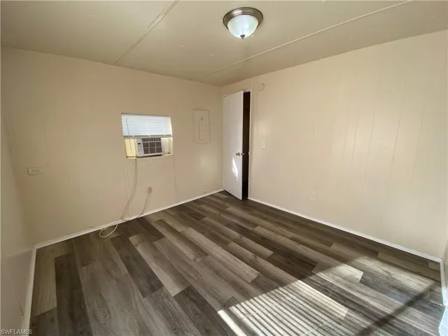 Spare room with dark wood-style flooring and cooling unit