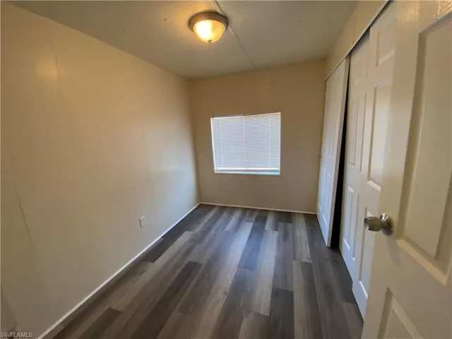 Unfurnished bedroom featuring dark wood finished floors and a closet