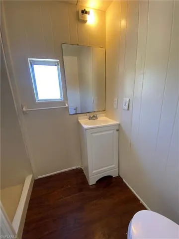 Full bath featuring vanity, dark wood finished floors, and a stall shower