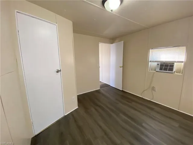 Unfurnished bedroom featuring dark wood-style flooring and cooling unit