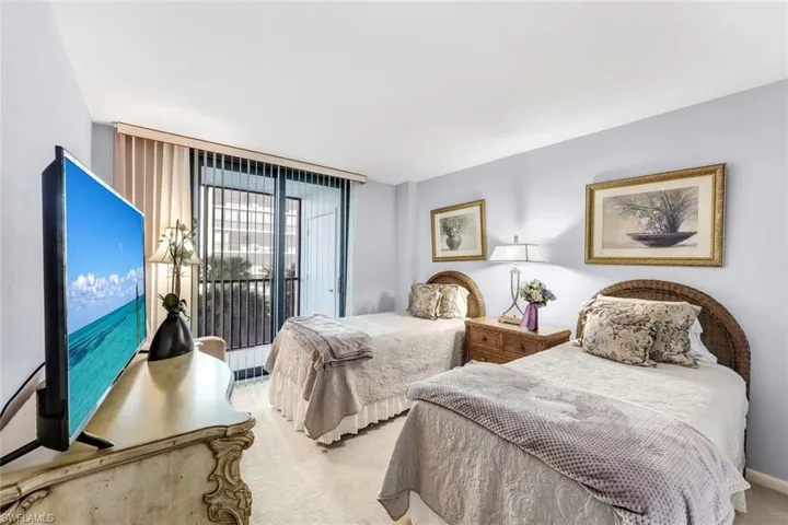 Sliding glass doors with vertical blinds, light blue wall paint, and wall-to-wall carpeting