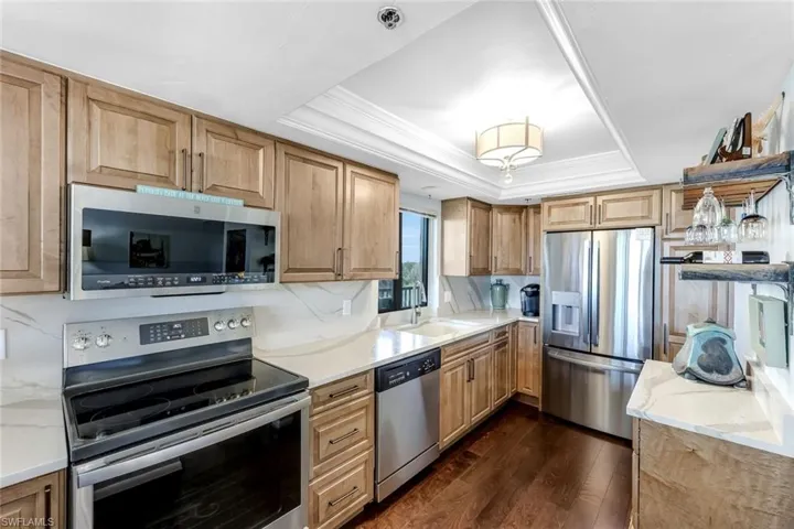 Kitchen featuring wood-finish cabinetry, stainless steel appliances, light countertops, and wood-finish flooring