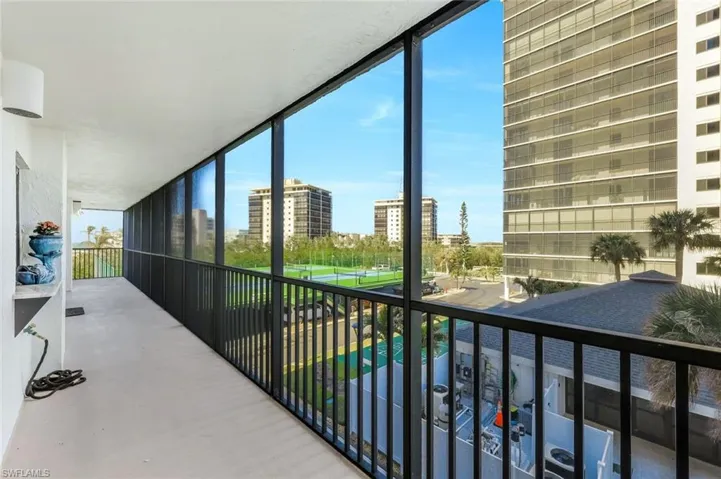Enclosed balcony with expansive windows, metal railing, and a textured ceiling