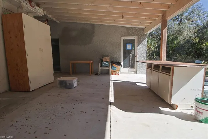 Covered patio area with concrete flooring, exposed wood beam ceiling, and textured exterior wall finish