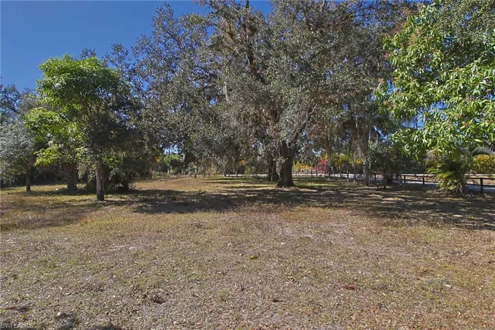 Expansive outdoor space featuring mature trees and partial fencing