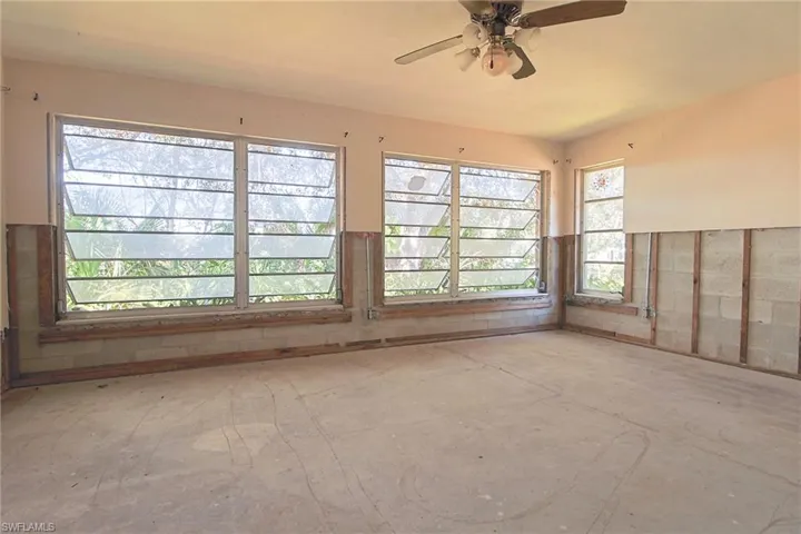 Room featuring multiple louvered windows, concrete flooring, and exposed concrete block walls