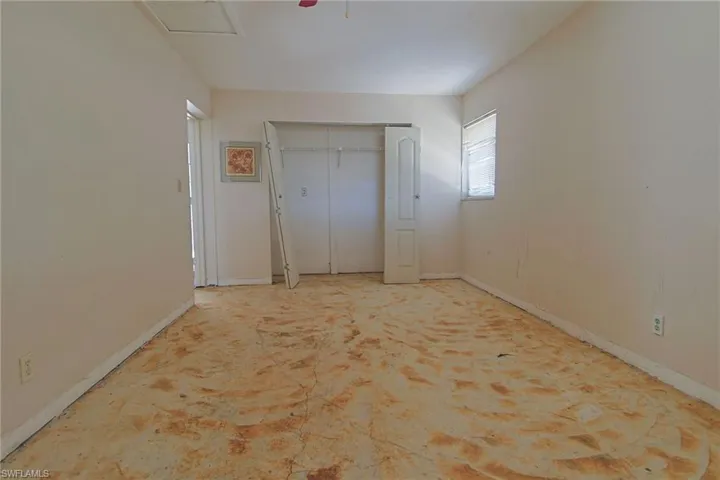 Spacious room featuring neutral painted walls, a standard window, a built-in closet with bi-fold doors, and a ceiling access panel