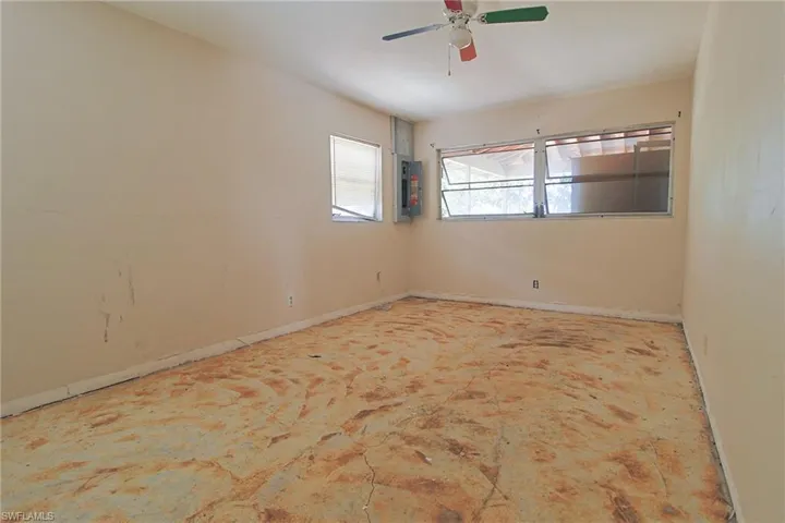 Spacious room featuring multiple windows, a ceiling fan, and exposed subflooring