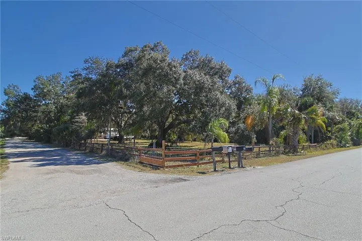 Corner lot with mature trees and a partial wooden fence