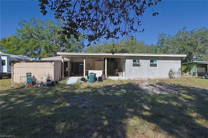 Rear exterior featuring a covered patio, stucco siding, and a wooden shed