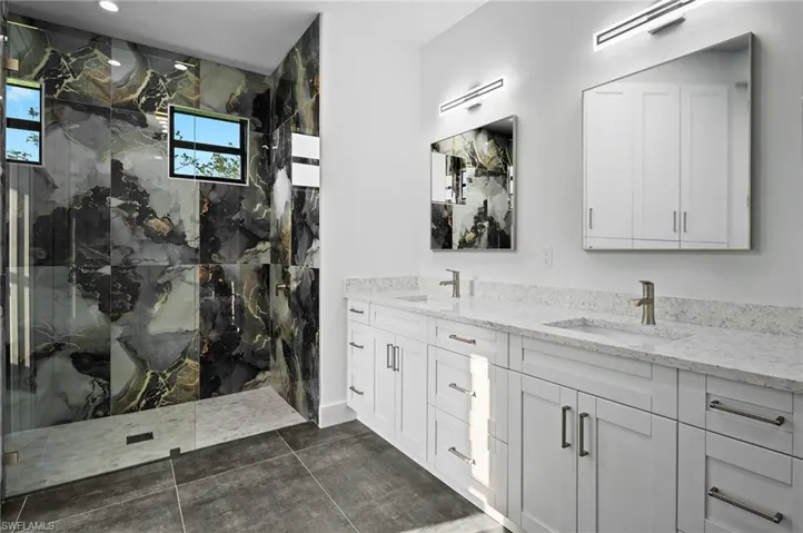 Full bathroom with a marble finish shower and double vanity