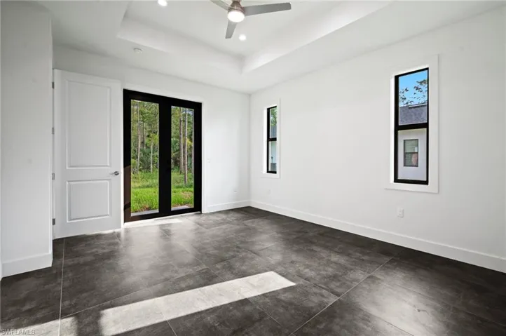 Empty room featuring plenty of natural light, ceiling fan, a tray ceiling, recessed lighting, and concrete flooring