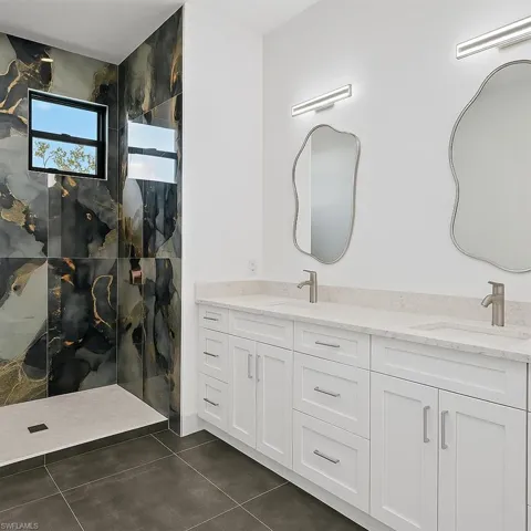 Bathroom with double vanity, a marble finish shower, and tile patterned flooring