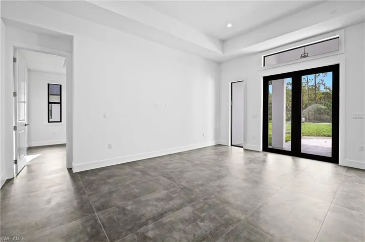 Empty room featuring healthy amount of natural light, concrete floors, recessed lighting, and a raised ceiling
