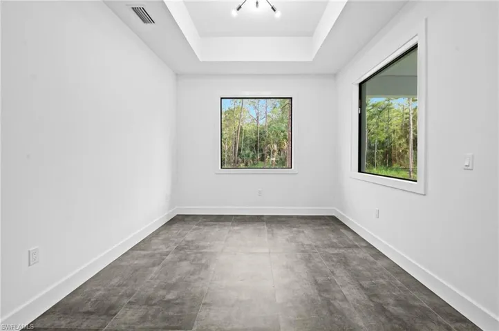 Empty room featuring healthy amount of natural light, a tray ceiling, and concrete flooring