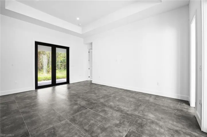 Unfurnished room featuring a tray ceiling and finished concrete flooring