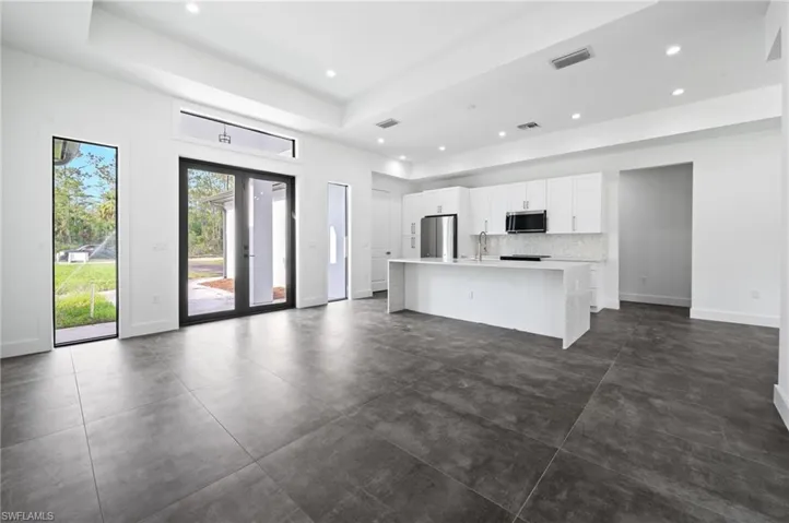 Unfurnished living room featuring recessed lighting, concrete flooring, and a tray ceiling