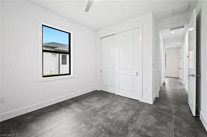 Unfurnished bedroom with finished concrete flooring, a closet, and a ceiling fan