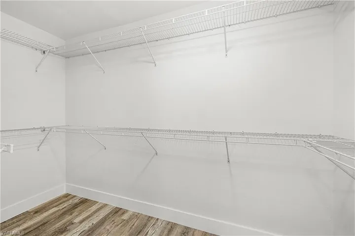 Spacious closet featuring multi-level wire shelving, white walls, white baseboards, and wood-finish flooring