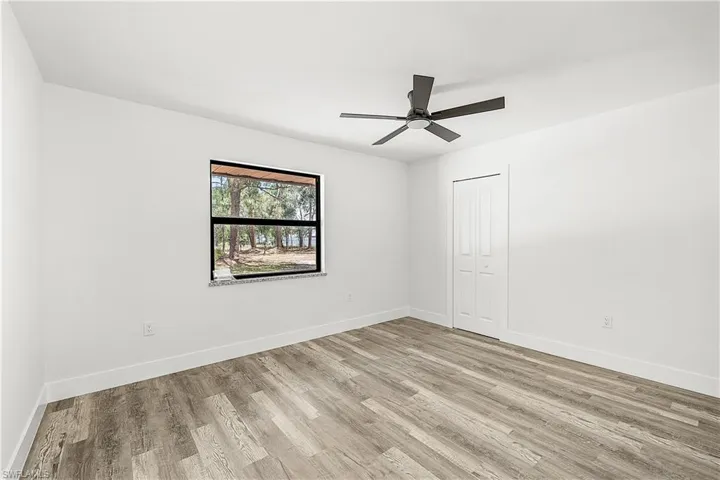 Room featuring wood-finish flooring, a contemporary ceiling fan, and a window with granite sill