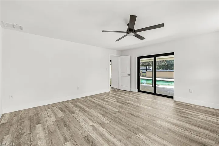 Spacious room featuring wood-finish flooring, white walls, and a contemporary ceiling fan