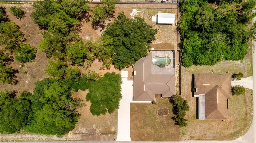 Expansive property featuring a screened-in swimming pool, a private driveway, and mature trees surrounding the main residence