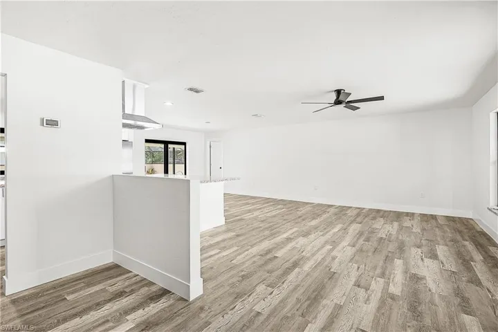 Open-concept living space featuring wood-finish flooring, a contemporary ceiling fan, and abundant natural light from the window
