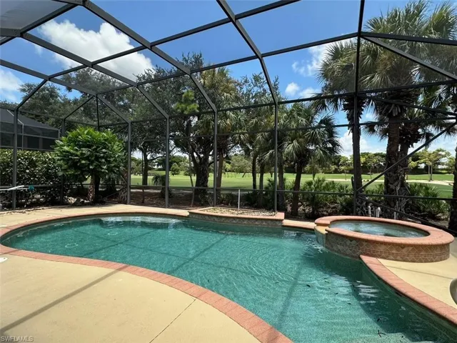 View of swimming pool featuring glass enclosure and an in ground hot tub