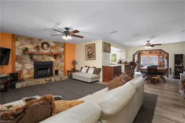 Living room featuring hardwood / wood-style flooring, ceiling fan, and a stone fireplace