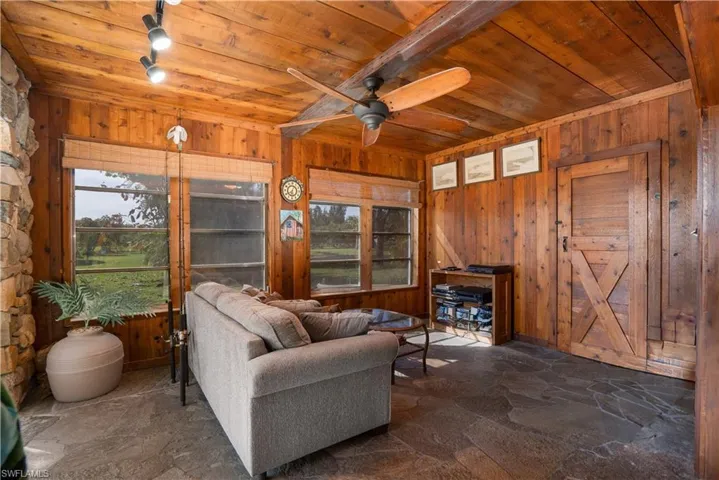 Living room with wood ceiling, ceiling fan, and wooden walls