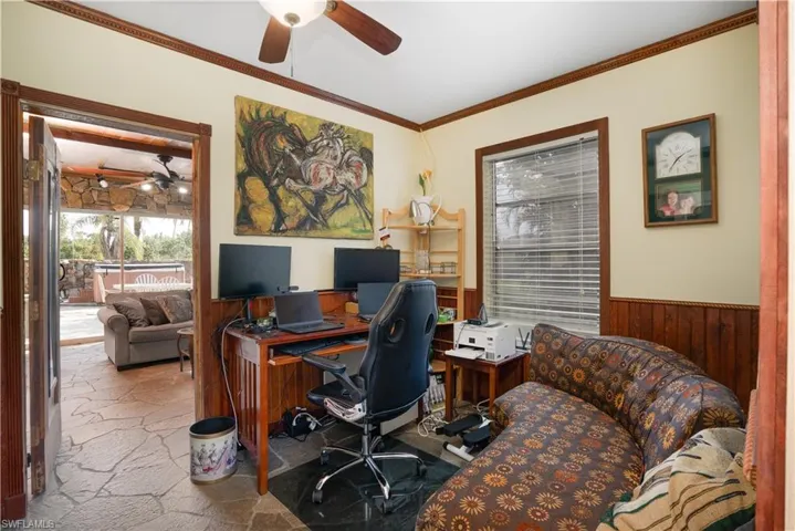 Office space with ceiling fan, ornamental molding, and wood walls