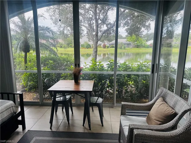 Sunroom / solarium with healthy amount of natural light, tile patterned floors, and a water view