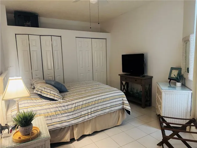 Bedroom featuring two closets, light tile patterned flooring, and ceiling fan